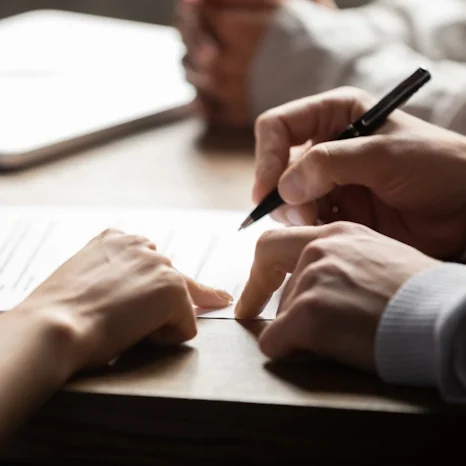 Attorney showing client where to sign on legal document