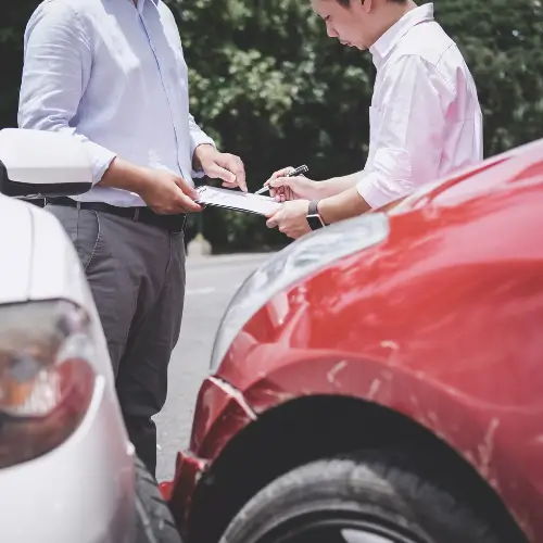 Man Filing an Automobile Defect Claim in Front of Two Crashed Cars