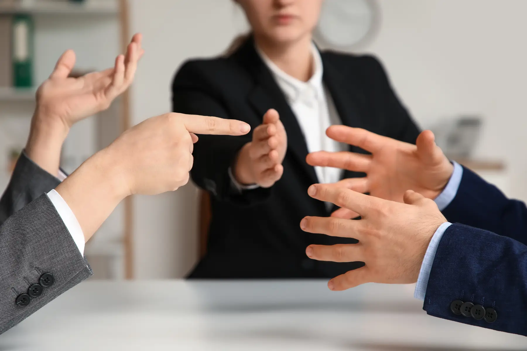 Female mediator in a business suit holding her hand out between two business people engaged in a business dispute